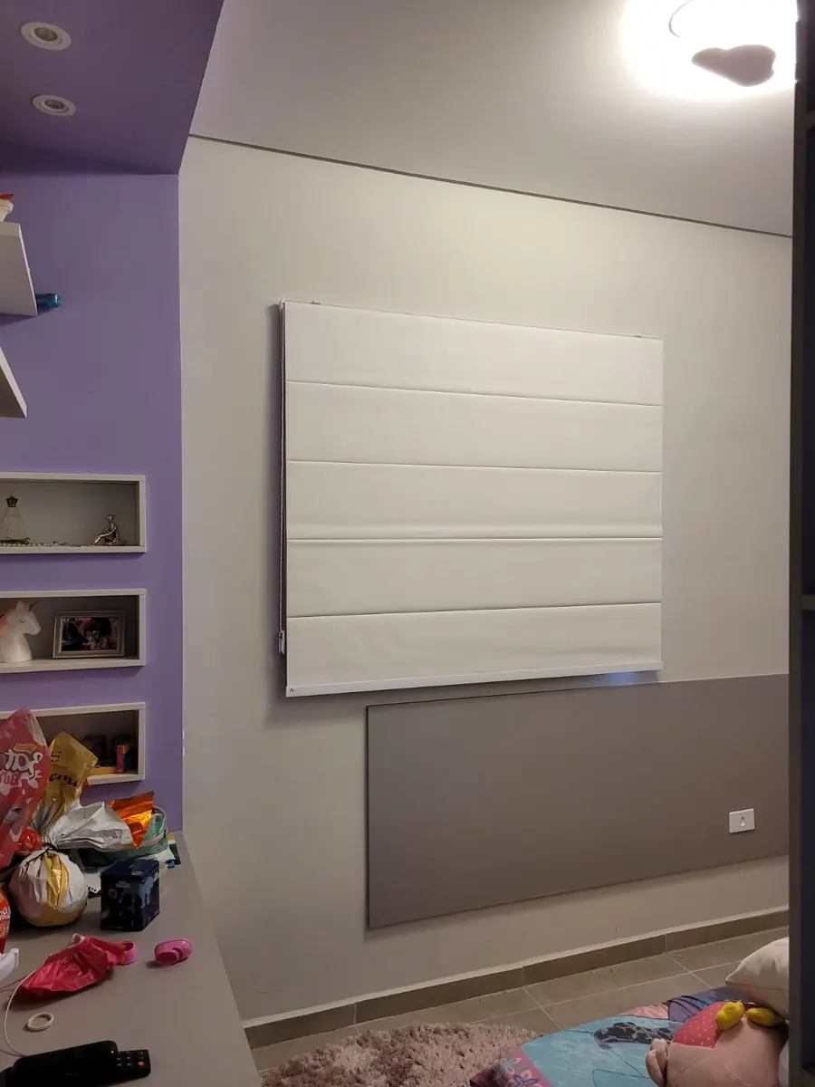 Persiana romana branca em quarto infantil com parede roxa e prateleiras decorativas, confeccionada pela Neusa