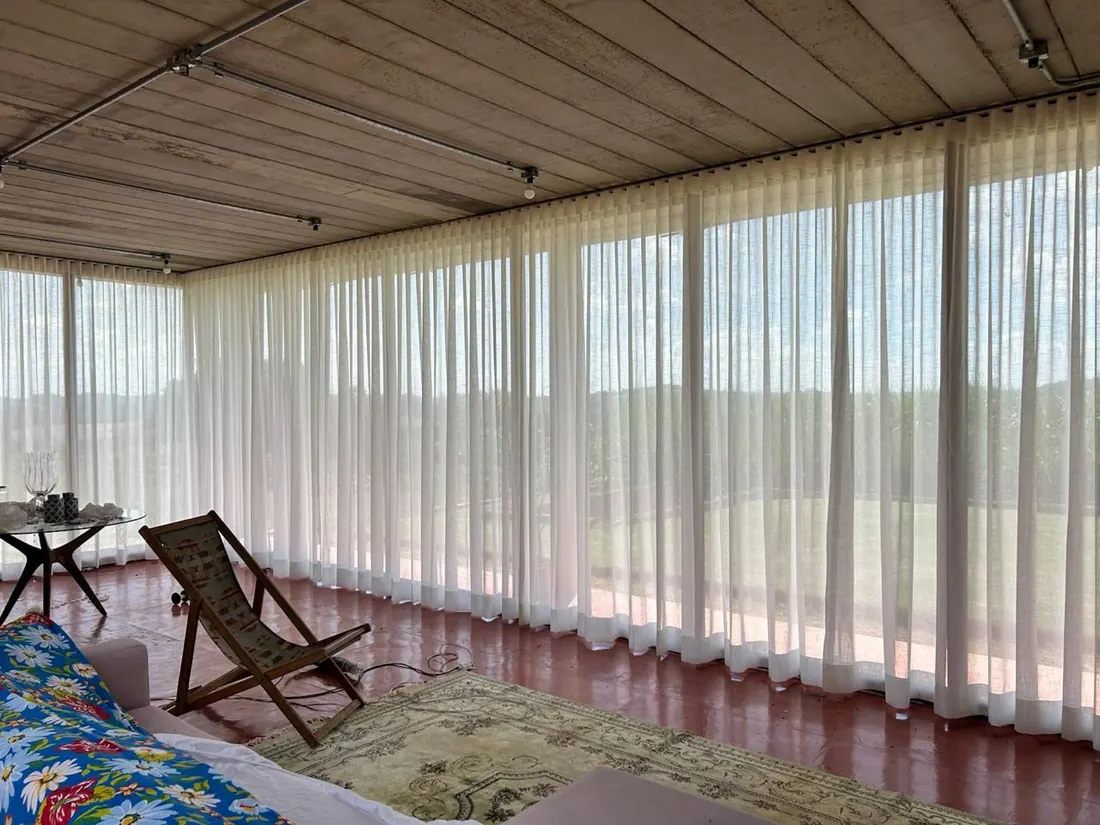 Cortinas longas de voile branco em varanda residencial — tecido do alto ao chão